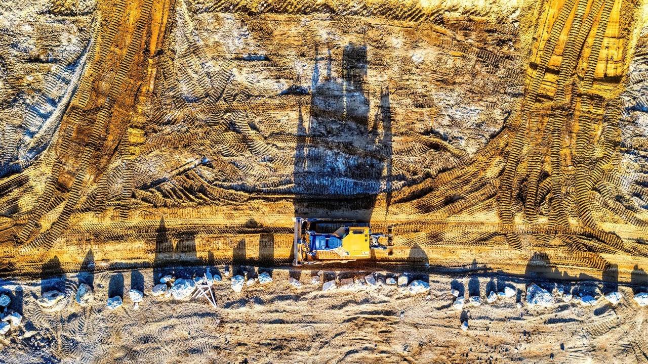 Excavadora vista desde arriba en una obra iluminada por el sol