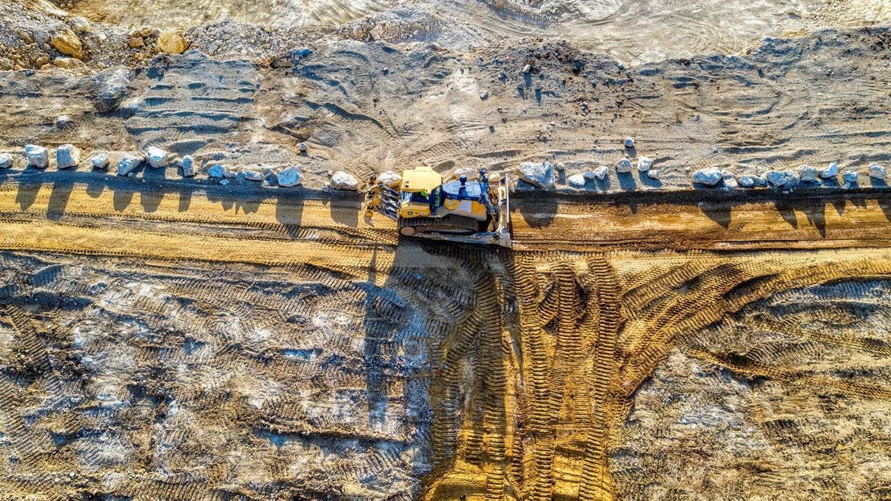 Vista aérea de una topadora en plena tarea sobre terreno arenoso