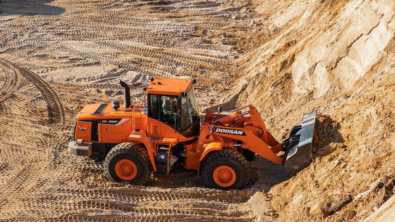 Cargadora frontal naranja trabajando sobre terreno arenoso, vista desde arriba