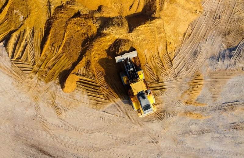 Excavadora trabajando sobre montículos de arena, vista con dron