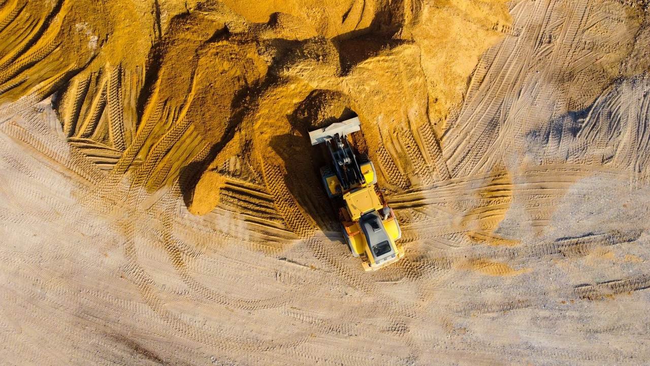 Excavadora trabajando sobre montículos de arena, vista con dron