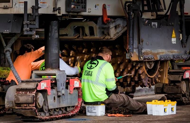 Técnicos haciendo mantenimiento a maquinaria de construcción en un taller industrial