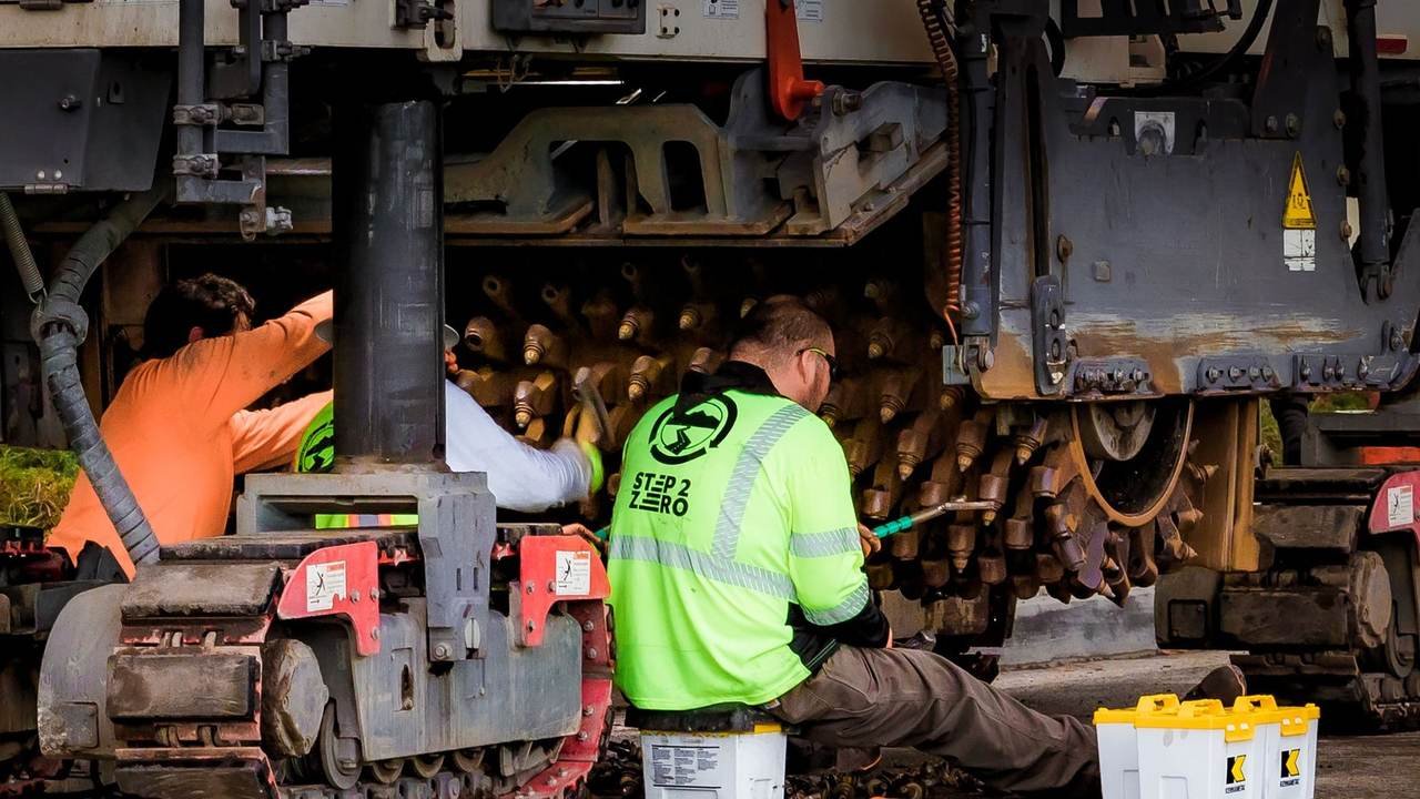 Técnicos haciendo mantenimiento a maquinaria de construcción en un taller industrial