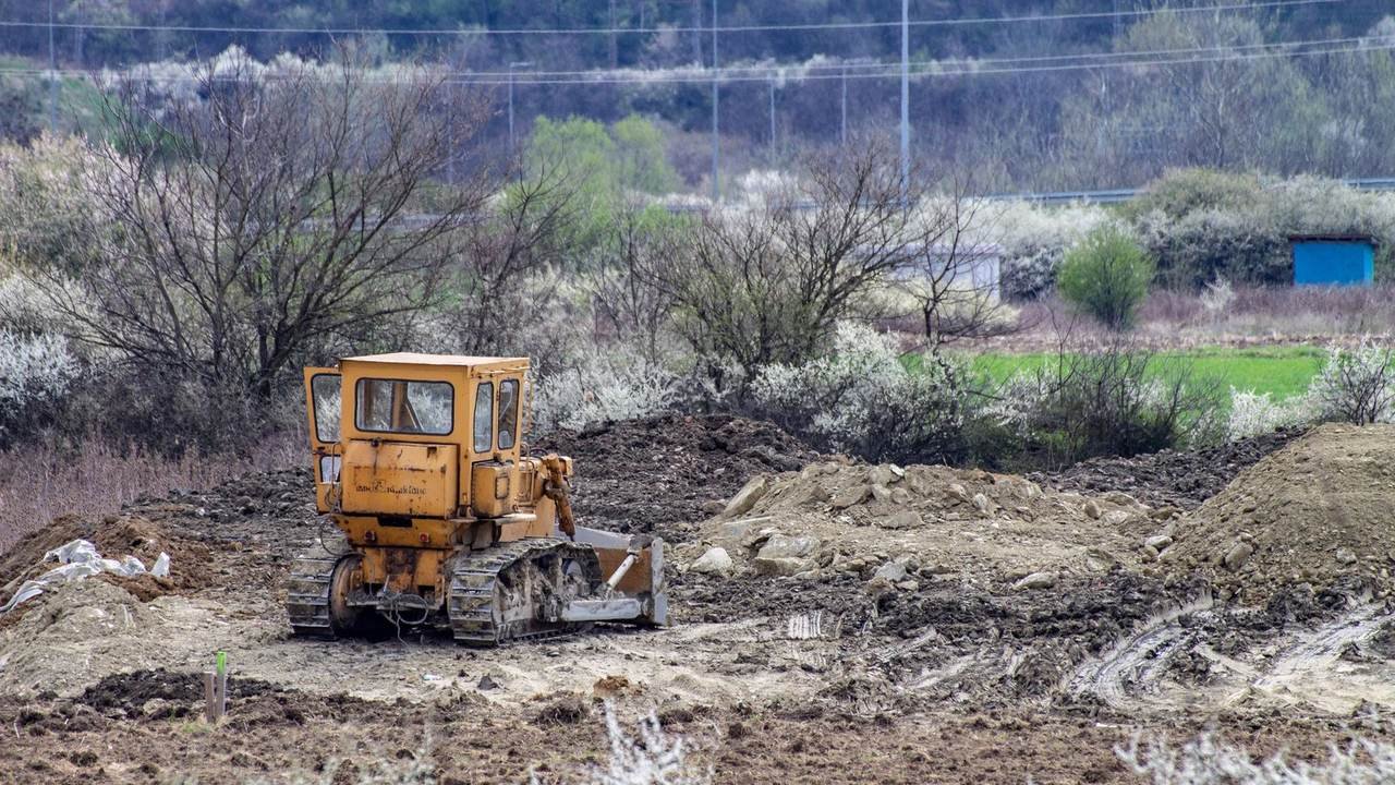 Topadora trabajando en una obra rural, con árboles y lomas de fondo