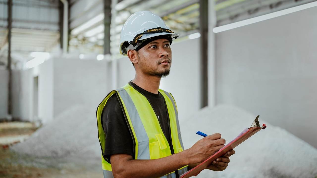 Operario usando una planilla de inspección dentro de una fábrica