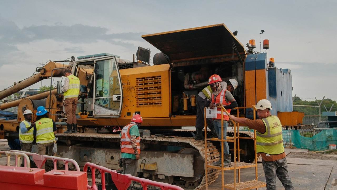Grupo de operarios con equipo de seguridad manipulando maquinaria en obra