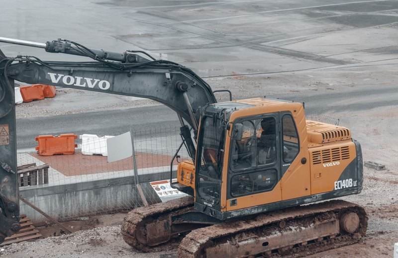 Excavadora Volvo amarilla en obra, con el tren de rodaje embarrado