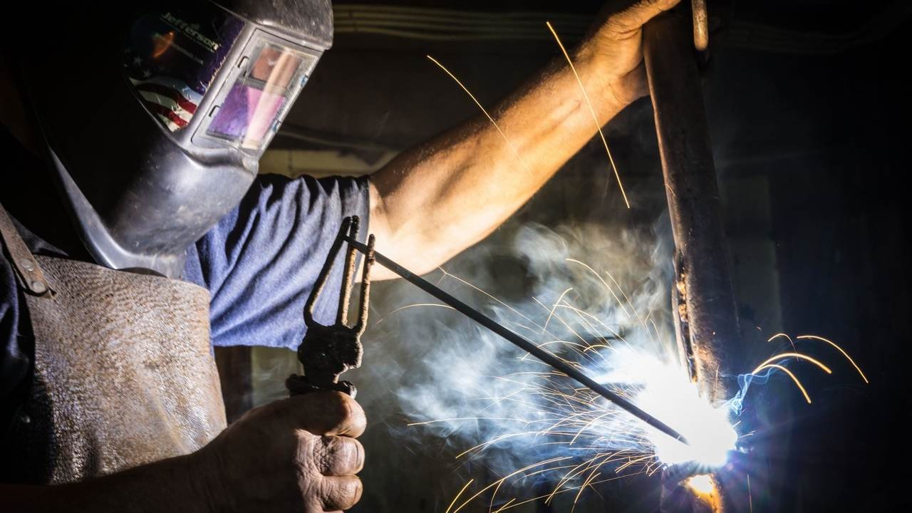 Primer plano de un soldador trabajando, con chispas saltando