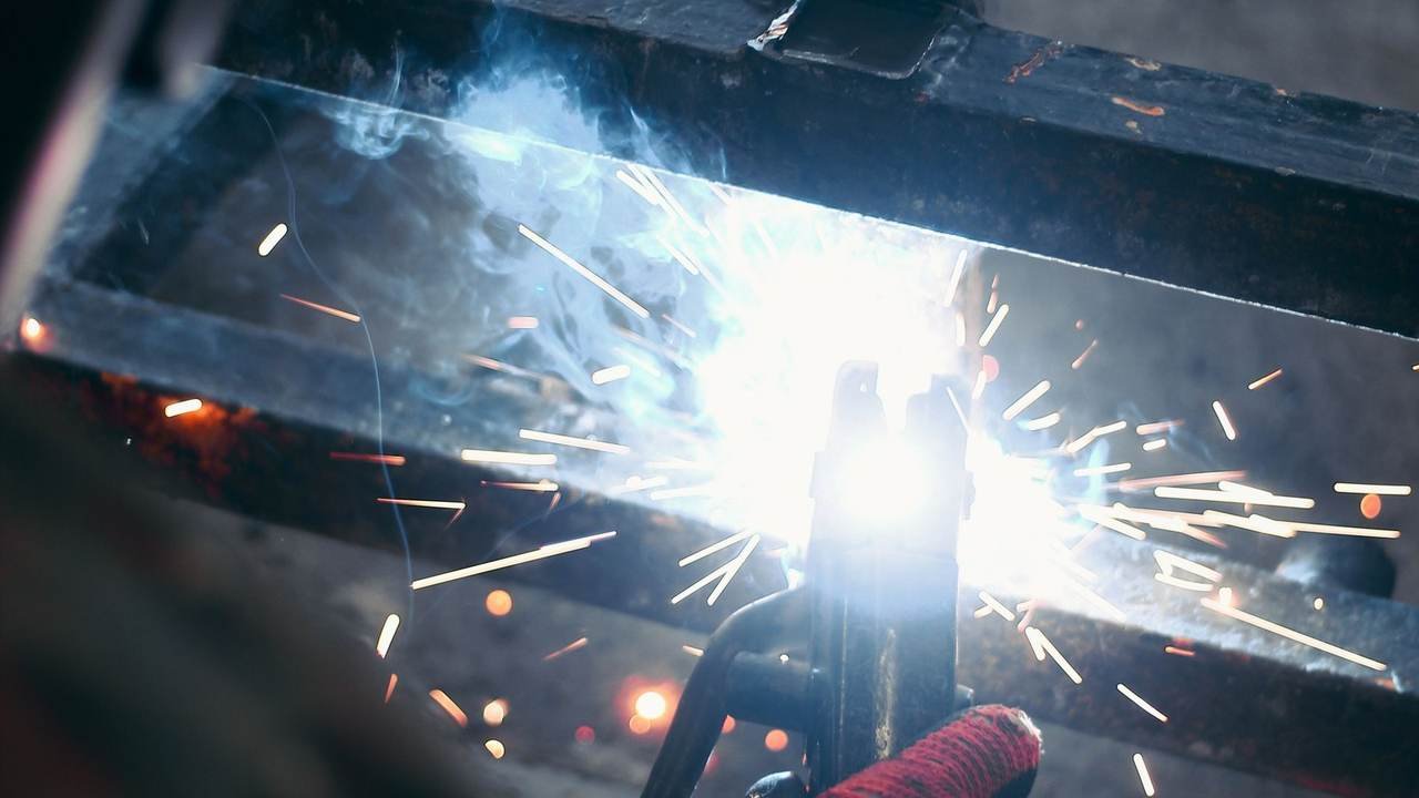Chispas de soldadura mientras un operario suelda metal en una fábrica