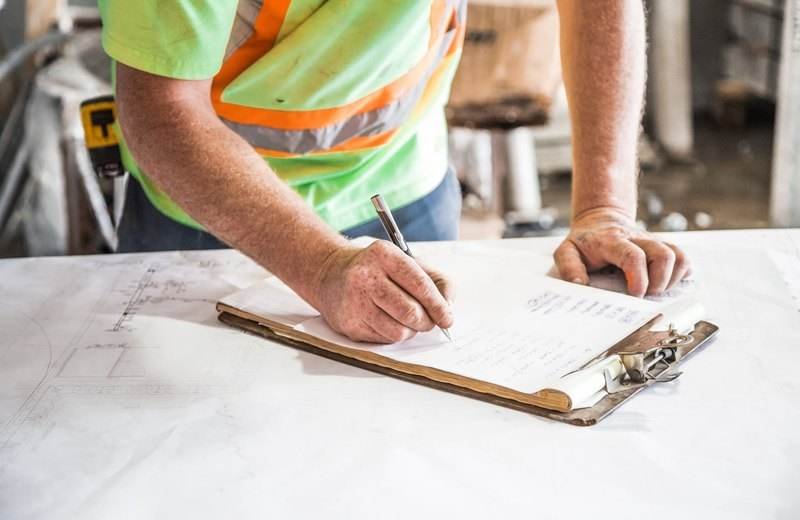 Operario tomando notas en una planilla dentro de una obra