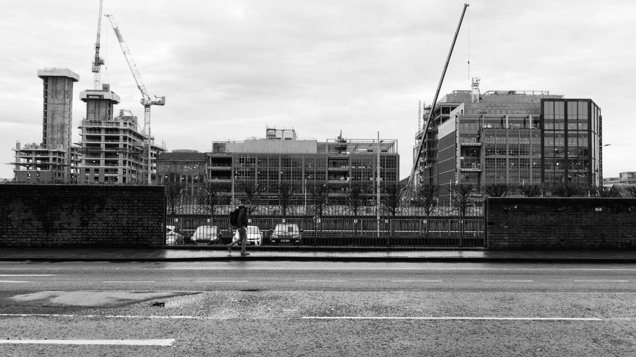 Obra con grúas y edificios en construcción, en blanco y negro