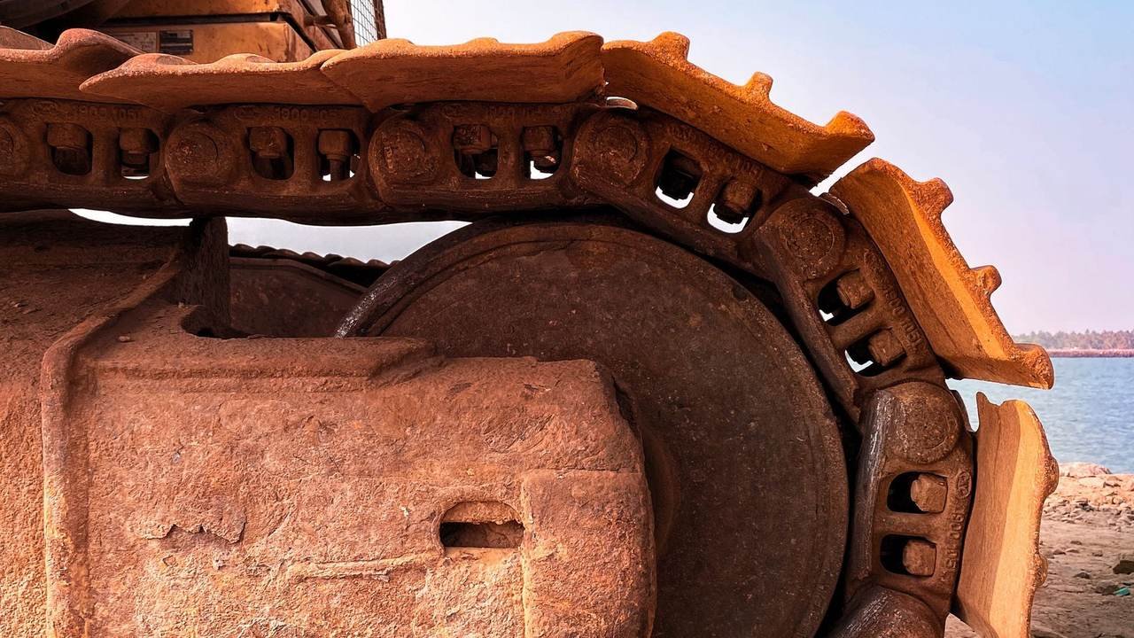 Detalle de una excavadora sobre terreno arenoso junto a la costa