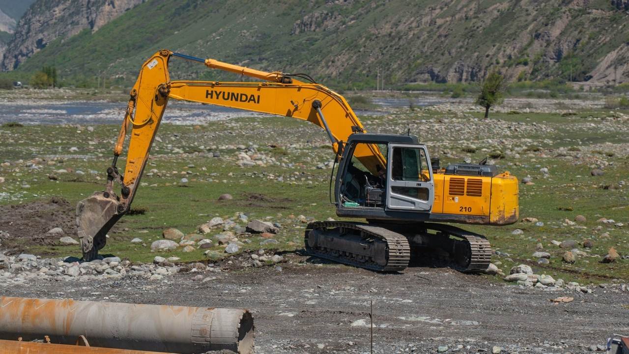 Excavadora amarilla operando en un paisaje montañoso y rocoso