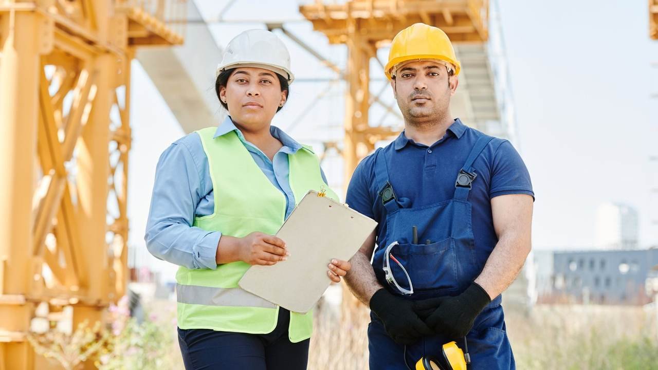 Dos ingenieros con casco y chaleco de seguridad en una obra
