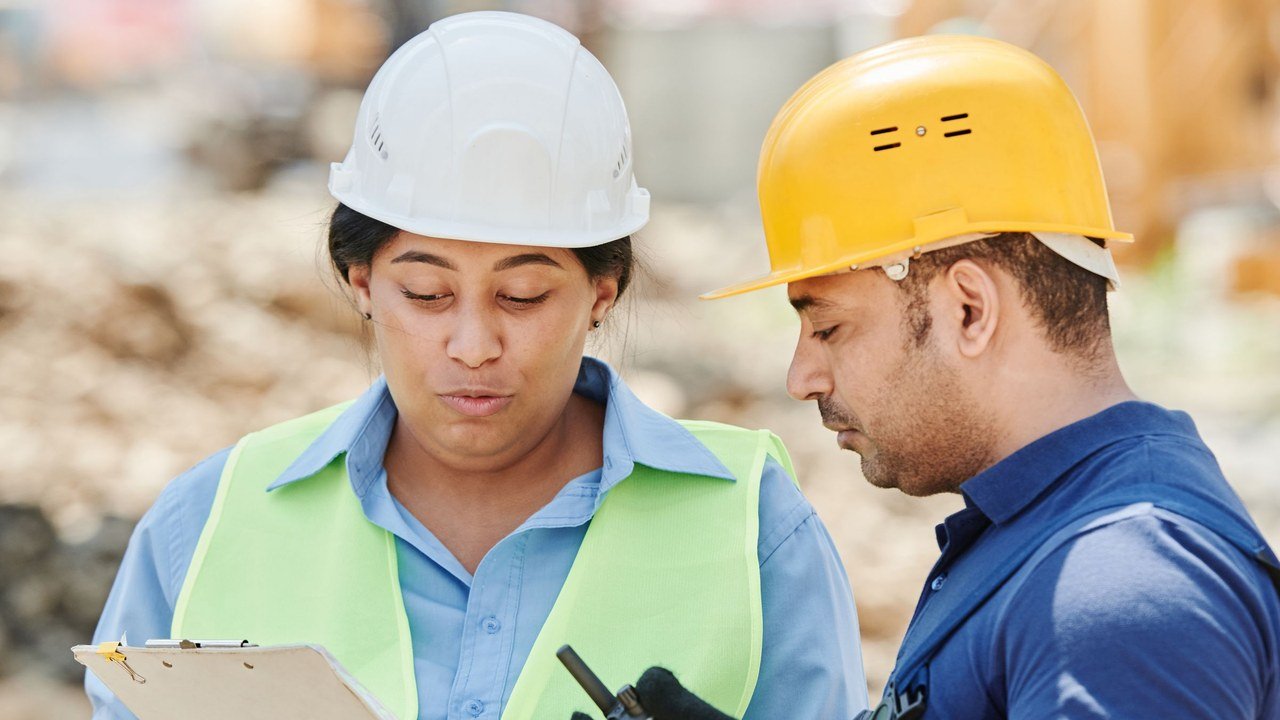 Dos trabajadores revisando un proyecto en obra con equipo de seguridad