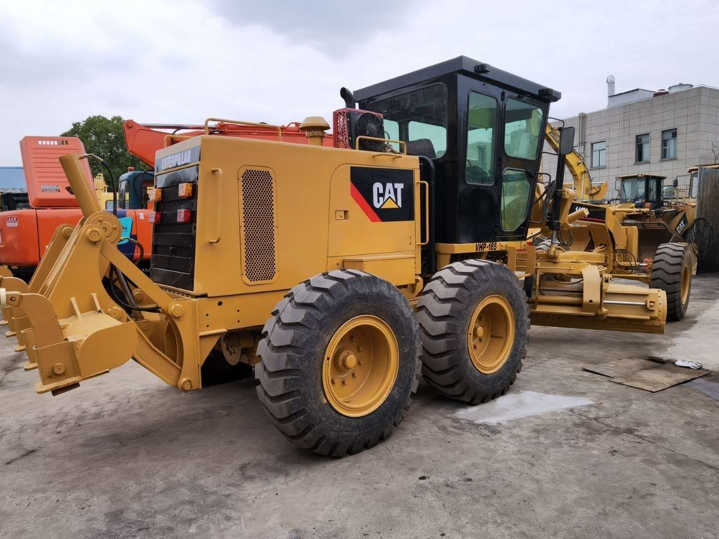 Motoniveladora Caterpillar usada en el patio, con más máquinas detrás